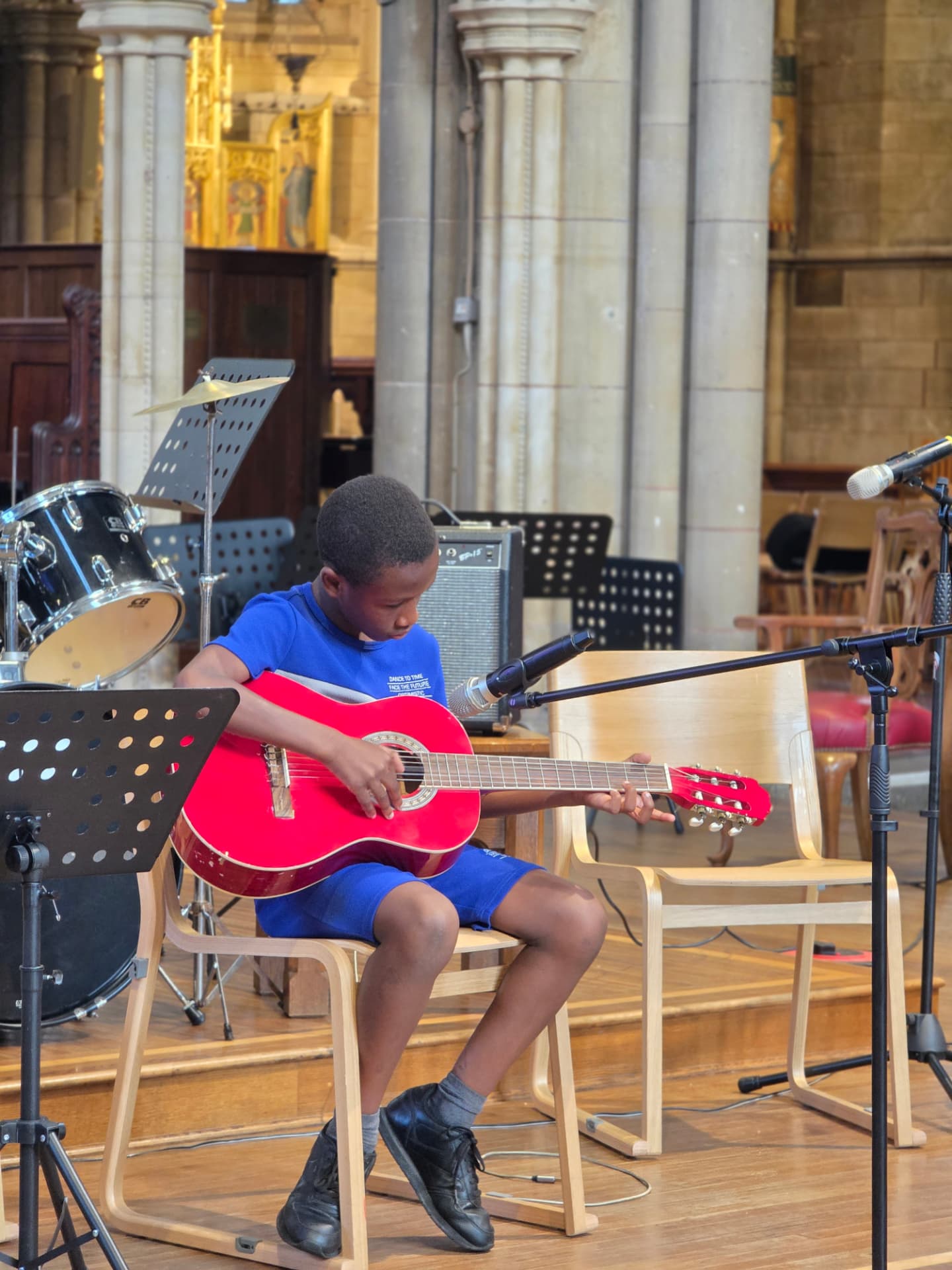 A boy playing a red guitar at the Summer Soirée